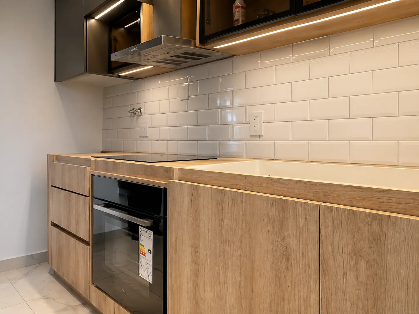 Detalle de bajomesada de roble con horno empotrado y revestimiento subway blanco